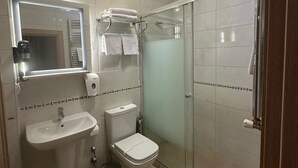A modern bathroom with a glass shower enclosure, a sink, toilet, and a mirror with built-in lighting.