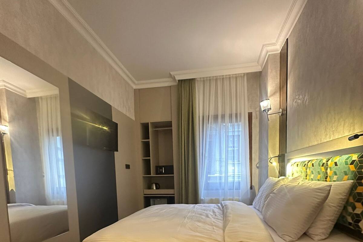A modern bedroom with a large bed, a bedside table, a TV, and a wardrobe.