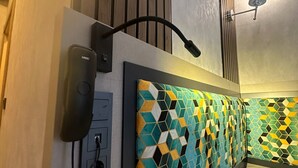 A hotel room with a patterned headboard, a phone, and a wall-mounted light fixture.