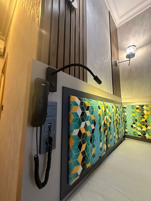 A hotel room with a patterned headboard, a phone, and a wall-mounted light fixture. - The Best City Kadikoy (Istanbul)