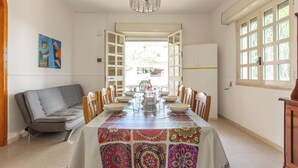 A dining room with a long table, chairs, a chandelier, and a view through an open door. - 4033 Villetta Stefy by Barbarhouse (Porto Cesareo)