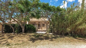 A building with a tiled roof and a gravel driveway leading to a gated entrance. - 4033 Villetta Stefy by Barbarhouse (Porto Cesareo)