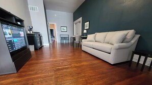 A modern living room with a flat-screen TV, a beige sofa, and a wooden floor. - The Loft on Winter - Downtown Adrian (Adrian)