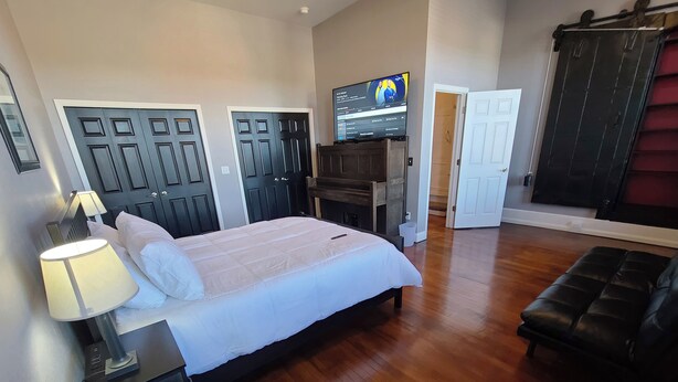 A bedroom with a bed, a TV, a desk, and a wardrobe. - The Loft on Winter - Downtown Adrian (Adrian)