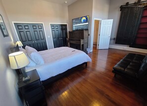 Quarto com cama, televisão, escrivaninha e guarda-roupa.