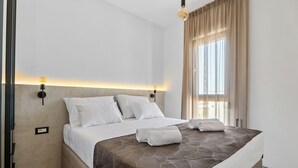 Une chambre d’hôtel moderne avec un grand lit, deux lampes fixées au mur, une fenêtre avec des rideaux et une prise de courant sur le mur.