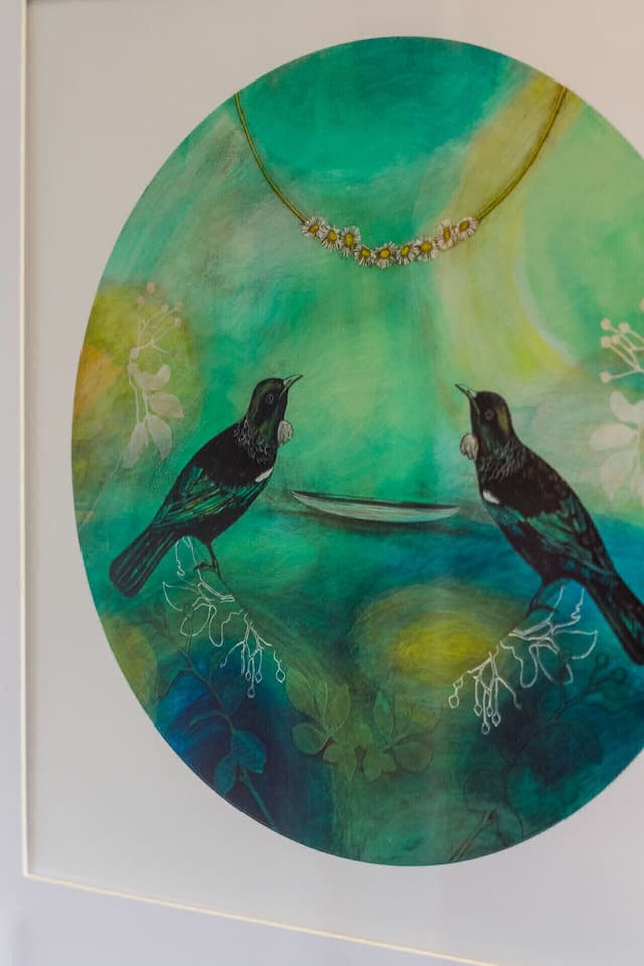 Une œuvre d’art de forme circulaire représentant deux oiseaux et des motifs floraux.