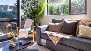 Uma sala de estar moderna com um sofá cinzento, uma mesinha e um vaso de planta.
