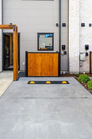 Entrada moderna de un edificio con un mostrador de recepción de madera, un espejo grande y un camino de concreto con pavimentación táctil amarilla.