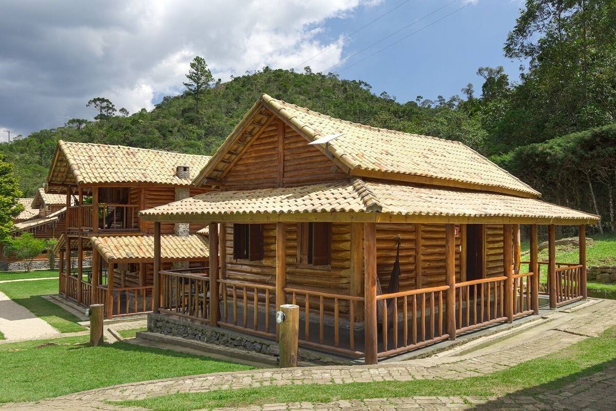 A wooden cabin with a tiled roof, a balcony, and a stone pathway leading to it.
