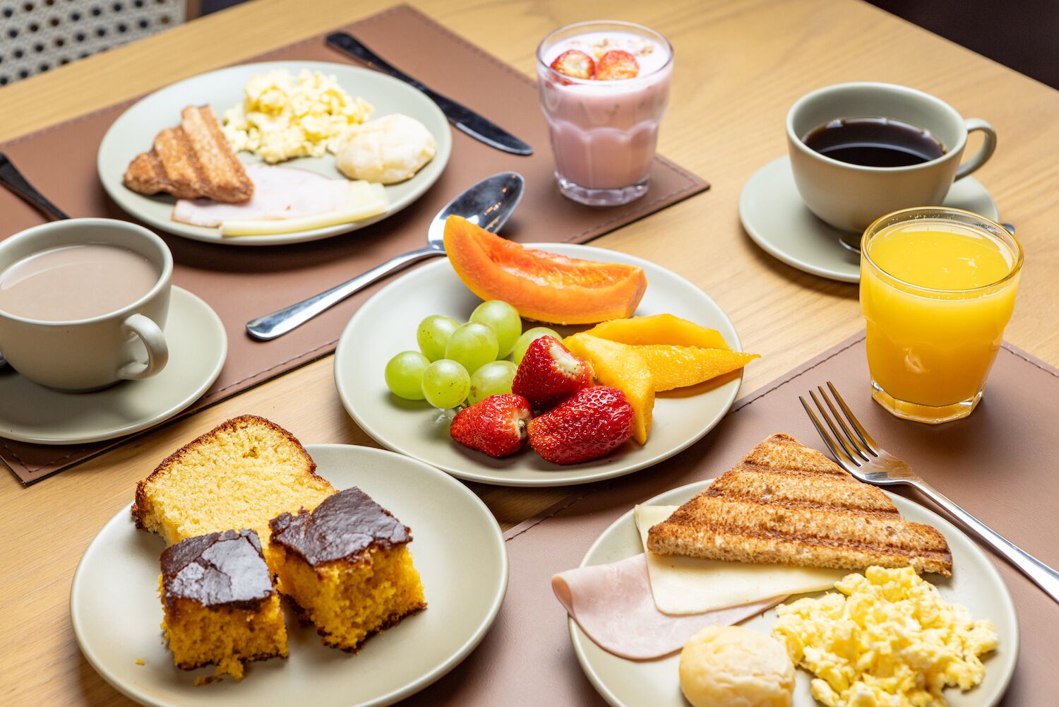 A breakfast setting with plates of food, a glass of orange juice, and a cup of coffee.