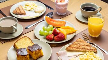 A breakfast setting with plates of food, a glass of orange juice, and a cup of coffee.