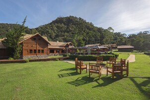 Un hotel de estilo cabaña de madera con asientos exteriores y vistas a una colina boscosa.
