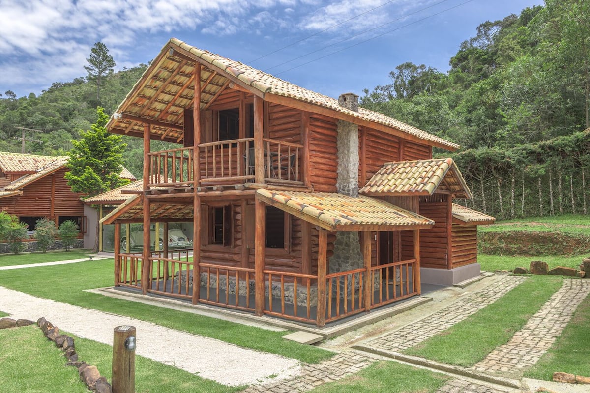 A two-story log cabin with a balcony and a stone foundation.
