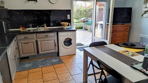 A compact kitchen with a washing machine, a sink, and a dining area with a table and chairs.