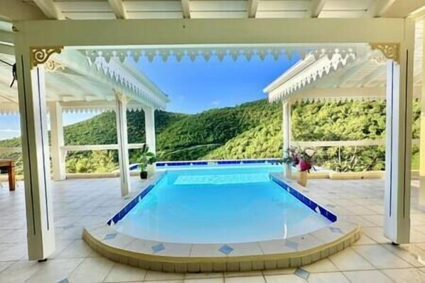 A covered swimming pool with a view of a mountainous landscape.