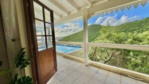 A room with a large window overlooking a pool and lush greenery. - Private 3bdr ocean view villa (Cole Bay)