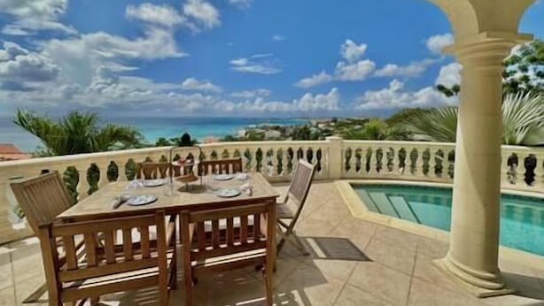 A covered outdoor dining area with a pool and ocean view. - Pelican Pearl Villa - GENERATOR (Sint Maarten)