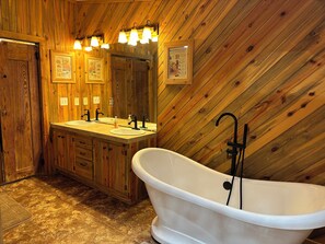Ein Badezimmer aus Holz mit freistehender Badewanne, zwei Waschbecken und einem großen Spiegel.