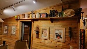A wooden interior with a shelf holding various items, a framed poster, and a sign indicating a laundry room.