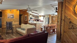 A cozy cabin interior with a wooden interior, a dining area, and a kitchenette.