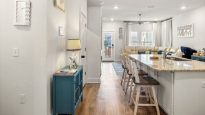 Una cocina moderna con una isla central, suelo de madera y vistas al comedor.