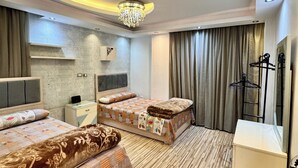 A hotel room with two beds, a vanity, a chandelier, and a large mirror.