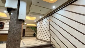 A modern staircase with a geometric light fixture, a handrail, and a patterned floor.