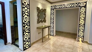 A spacious hallway with a marble floor, decorative black and gold panels, and a mirror on the wall.