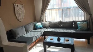 Ein Wohnzimmer mit einer Couch, einem Couchtisch und einer Wandweberei aus Fransen.