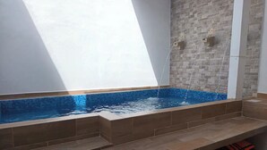 Ein Schwimmbecken mit Stufen, einer gefliesten Wand und einem Fenster, das natürliches Licht hereinlässt.