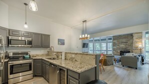 A modern kitchen with granite countertops, stainless steel appliances, and a stone accent wall.