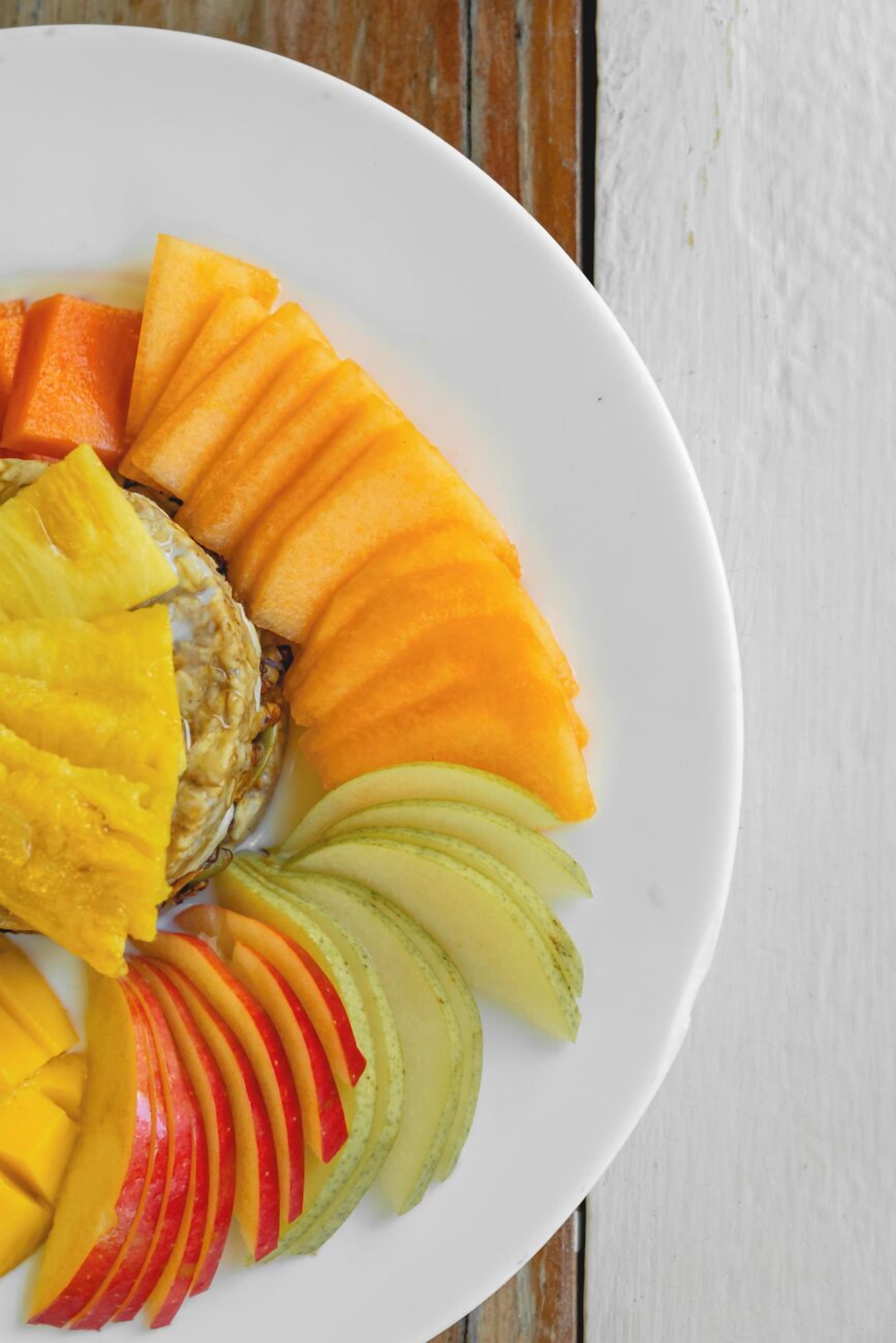 A white plate with sliced fruits arranged in a semi-circle.