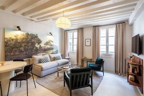 Un salon moderne avec un canapé, une table basse, des fauteuils et un tableau au mur.