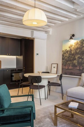 Uma sala de estar moderna com uma mesa de jantar redonda, duas cadeiras, um sofá e uma mesa de centro.