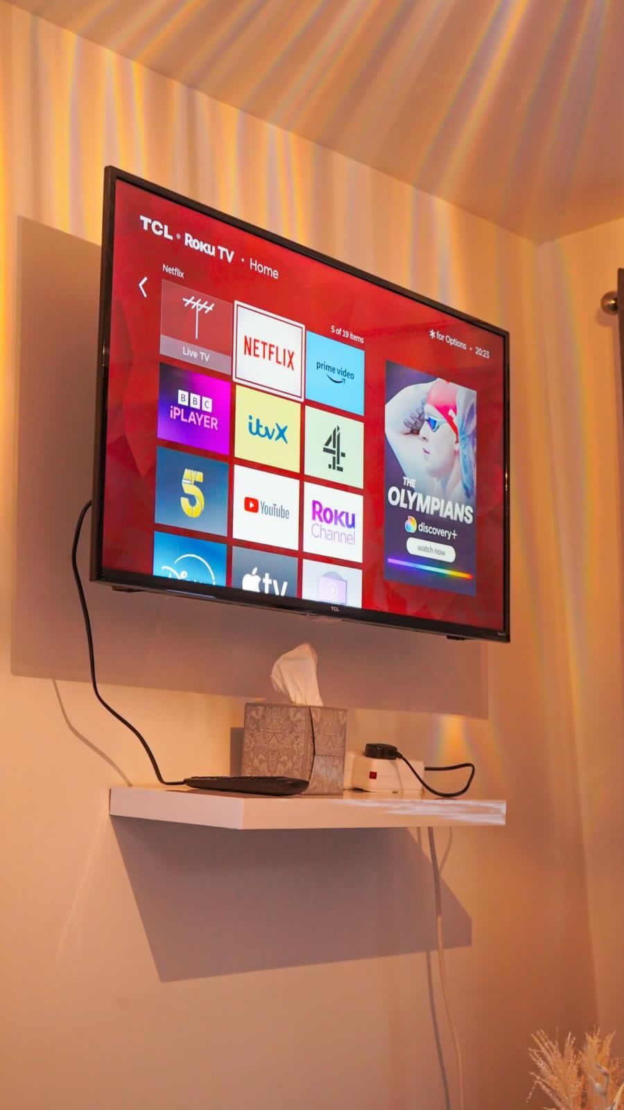 A television mounted on a wall displaying various streaming services.