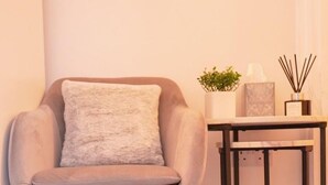 Ein Sessel mit Kissen, ein kleiner Tisch mit Pflanze, Kerze und Diffusor.