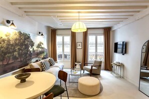Una sala de estar moderna con un sofá, sillones, una mesa redonda y un televisor.