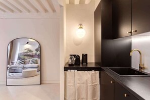 A modern kitchen with a black countertop, a gold faucet, and a coffee maker.