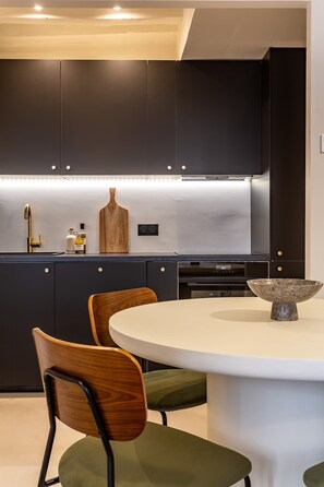 Una cocina moderna con gabinetes oscuros, una encimera blanca y una mesa redonda con sillas.