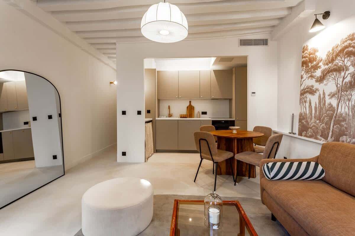 Ein modernes Wohnzimmer mit einem runden Couchtisch, einer Couch mit gestreiftem Kissen und einem Essbereich mit Stühlen und Tisch.