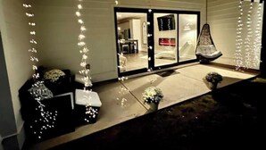 Una casa con puerta corrediza de vidrio, una planta en maceta y una silla colgante en el exterior.