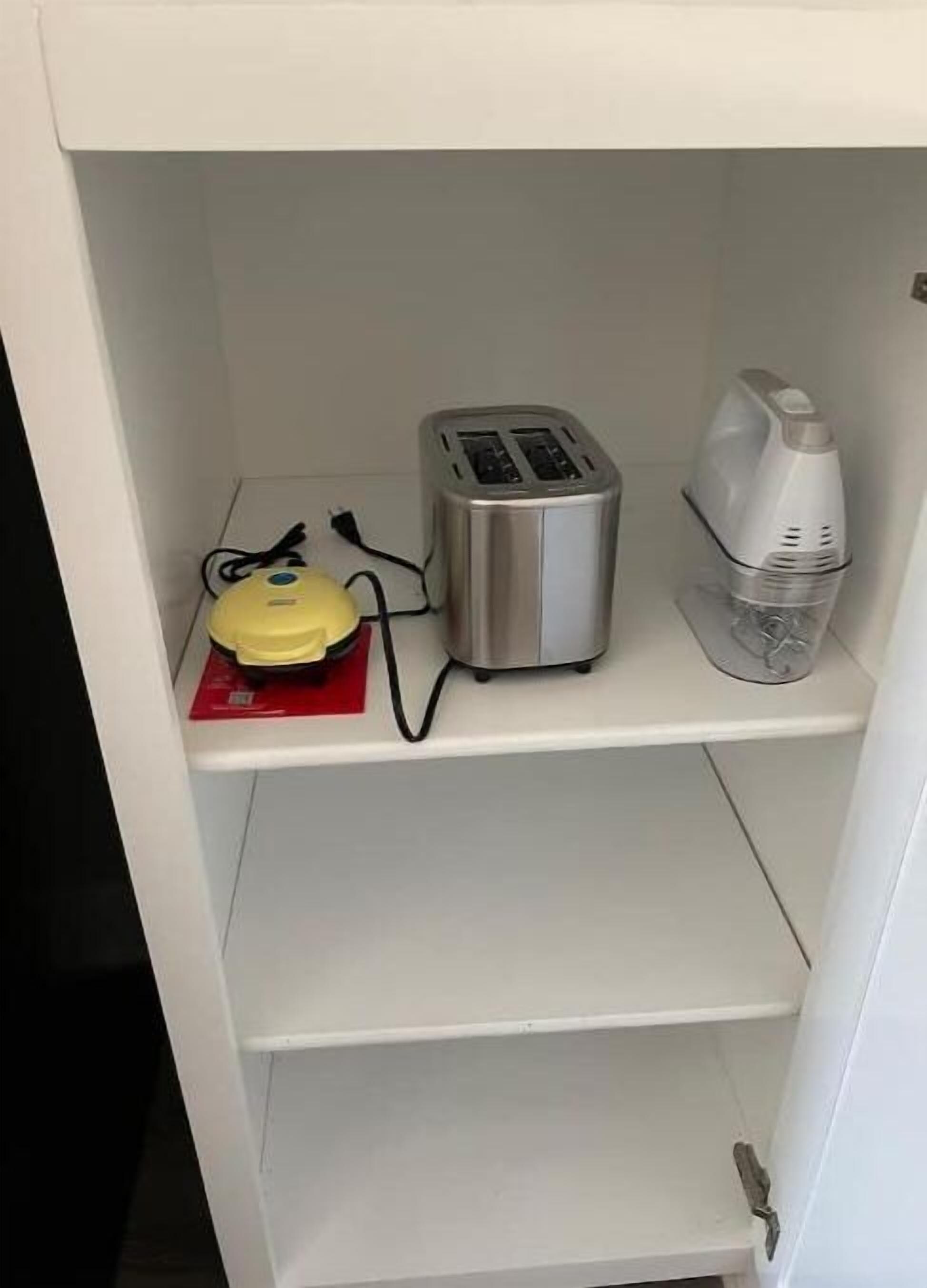 A white shelf with a toaster, a yellow appliance, and a white device.