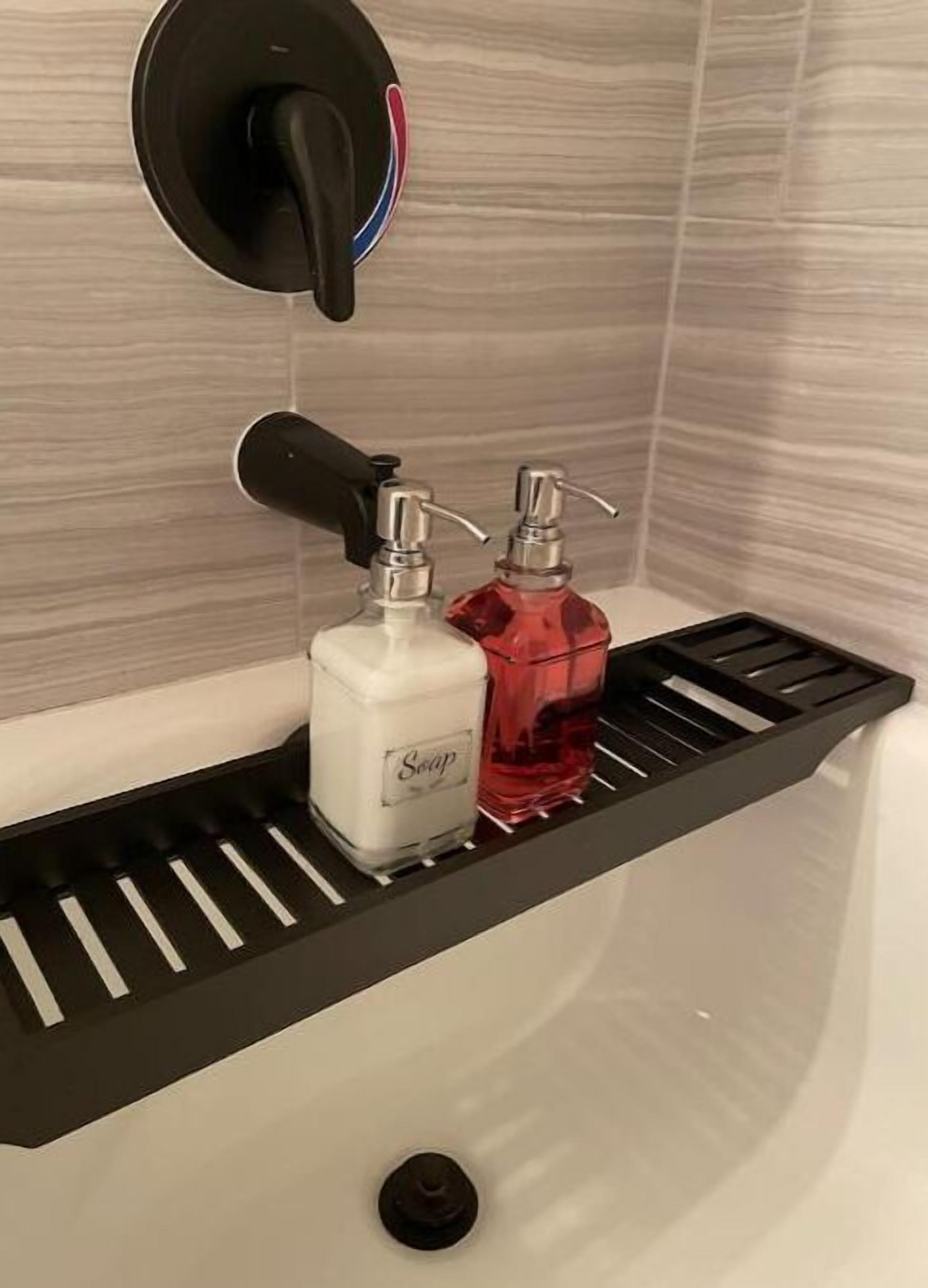 Une salle de bain avec une étagère noire sur laquelle sont posés deux distributeurs de savon, l’un portant l’étiquette « Savon » et l’autre étant de couleur rouge.