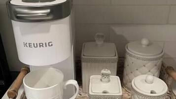 Una bandeja con una cafetera Keurig, una taza blanca, una tetera blanca y dos recipientes blancos.