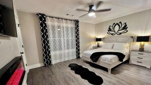 Ein modernes Schlafzimmer mit Bett, Nachttischen, Deckenventilator und einer Wanddekoration.