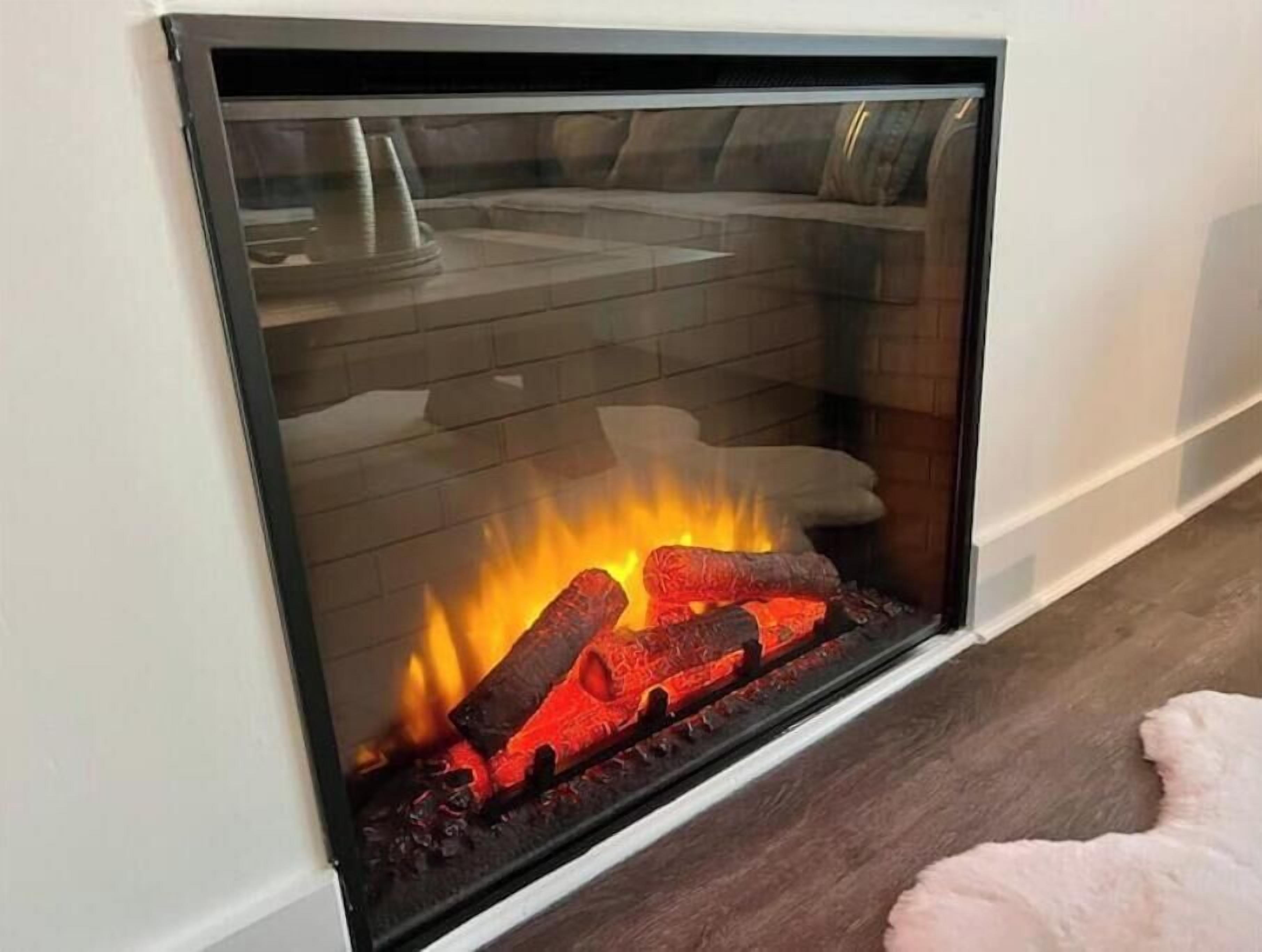 A modern fireplace with a glass front, burning logs, and a white wall.