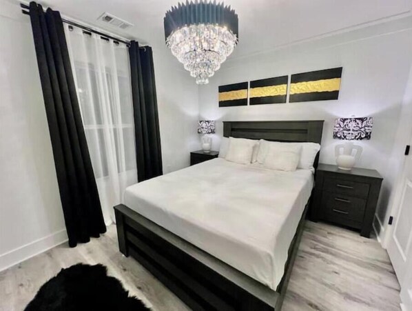 A modern bedroom with a large bed, a chandelier, and artwork on the wall. - Gorgeous view house (Gainesville)