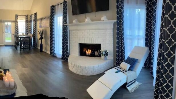 A modern living room with a fireplace, a dining area, and a seating area with a white sofa.