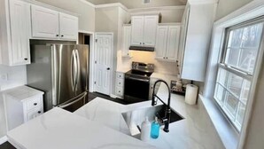 A modern kitchen with white cabinetry, stainless steel appliances, and a window providing natural light.